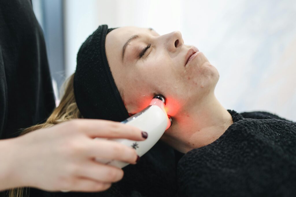 Frau erhält eine Gesichtspflege Behandlung mit roter Lichttherapie, eine moderne Technik zur Förderung einer gesunden und klaren Haut.