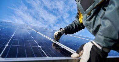 Nahaufnahme eines Technikers in Arbeitshandschuhen, der unter einem wunderschönen blauen Himmel mit Wolken eine eigenständige Photovoltaik-Solaranlage installiert. Konzept alternativer Energie und nachhaltiger Energieressourcen