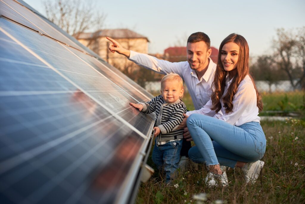 Eine Familie steht vor einer Solaranlage, die von einem SMA Sunny Tripower betrieben wird. Der Vater zeigt auf die Solarpanels, während das Kind neugierig die Anlage berührt, symbolisierend die Bedeutung von Solarenergie und nachhaltigem Energiemanagement für künftige Generationen.