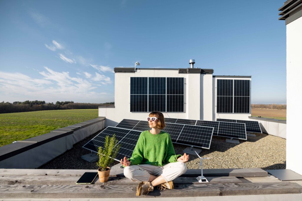 Eine Frau sitzt entspannt auf einem Dach mit installierten Solarpanels, die von einem SMA Sunny Tripower Wechselrichter unterstützt werden. Die Szene symbolisiert die Ruhe und Nachhaltigkeit, die durch den Einsatz von Solarenergie und intelligentem Energiemanagement erreicht werden können.