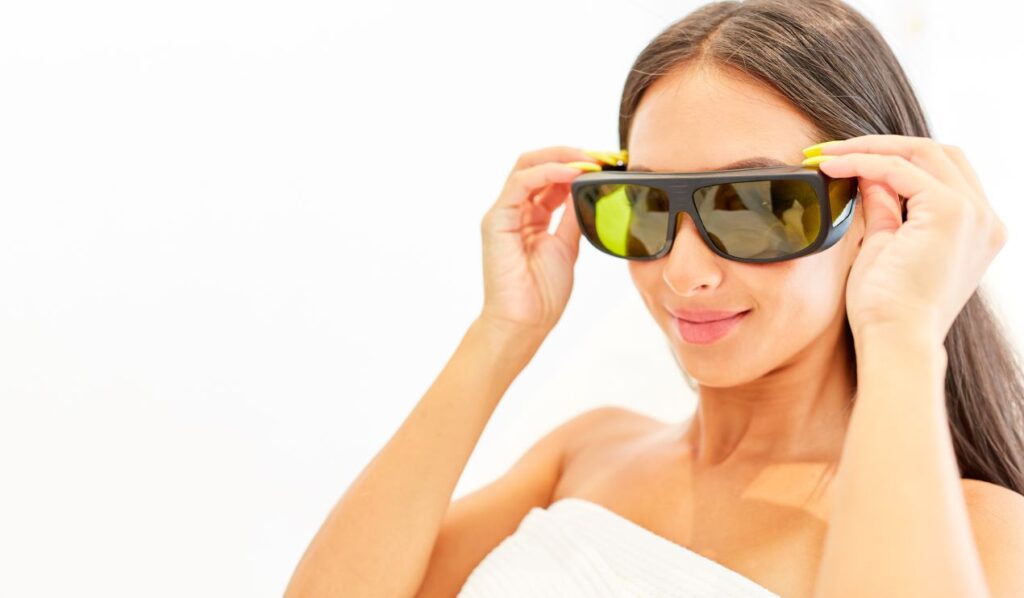 Nahaufnahme einer Frau mit Schutzbrille, die sich auf eine Laserenthaarungsbehandlung vorbereitet.