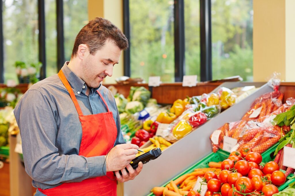 Ein Supermarktmitarbeiter nutzt ein MDE-Gerät zur Bestandskontrolle im Obst- und Gemüsebereich.