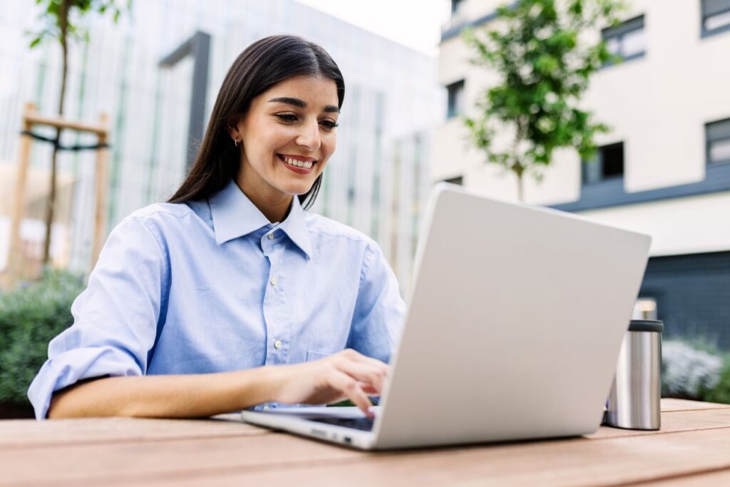 Junge Frau arbeitet konzentriert am Laptop im Freien – Tipps, wie man eine Masterarbeit schreiben lassen kann und welche Alternativen es gibt.