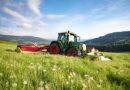 Traktor mit Anbaugeraet auf weiter Bergwiese – idealer Einsatzort fuer einen Flaechenhaecksler kaufen-Vergleich