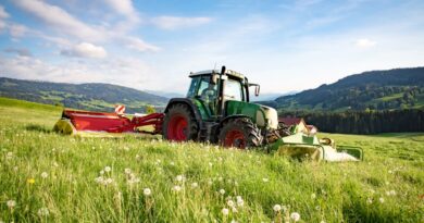Traktor mit Anbaugeraet auf weiter Bergwiese – idealer Einsatzort fuer einen Flaechenhaecksler kaufen-Vergleich