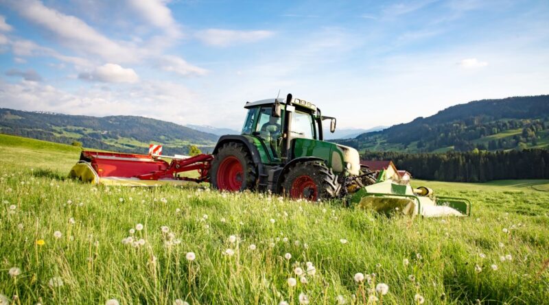Traktor mit Anbaugeraet auf weiter Bergwiese – idealer Einsatzort fuer einen Flaechenhaecksler kaufen-Vergleich