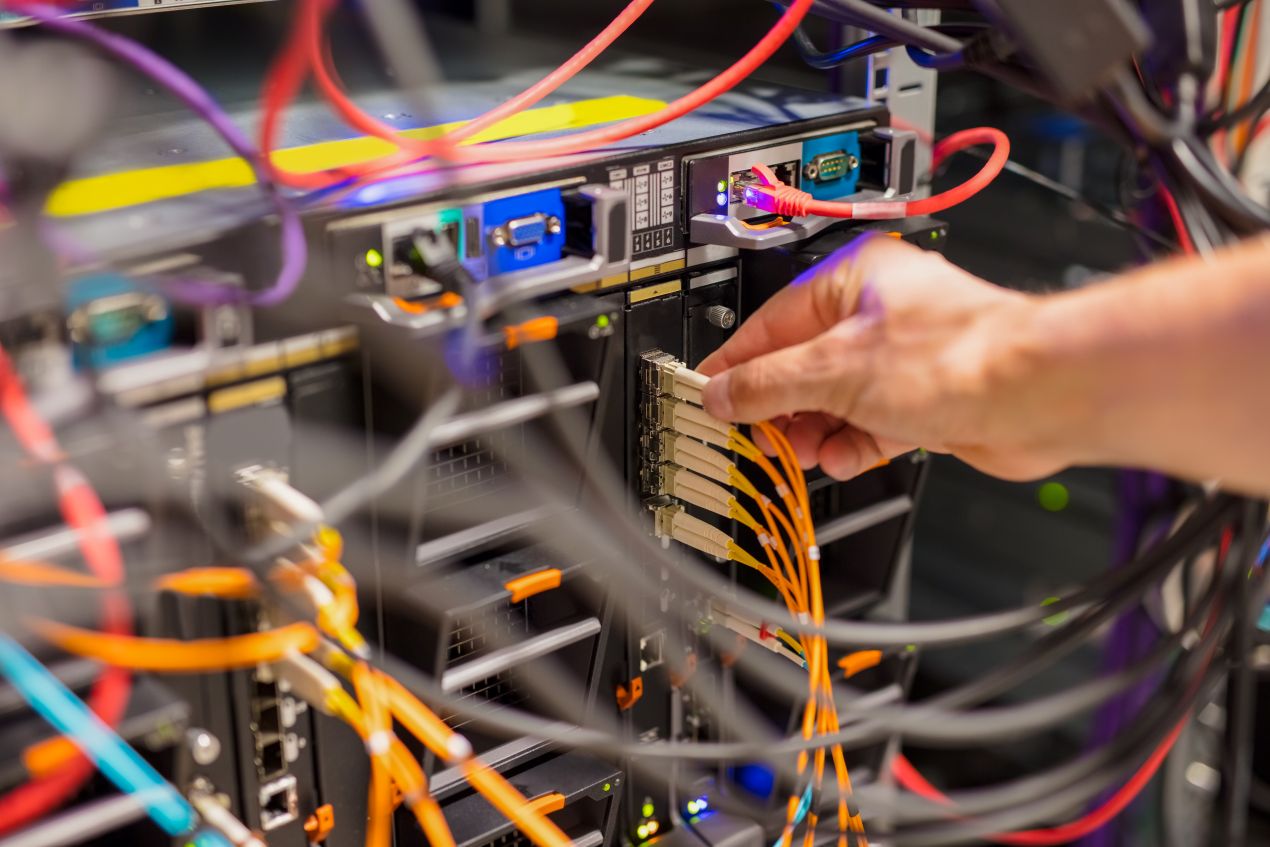 Techniker verbindet Transceiver mit Glasfaserkabel im Rechenzentrum