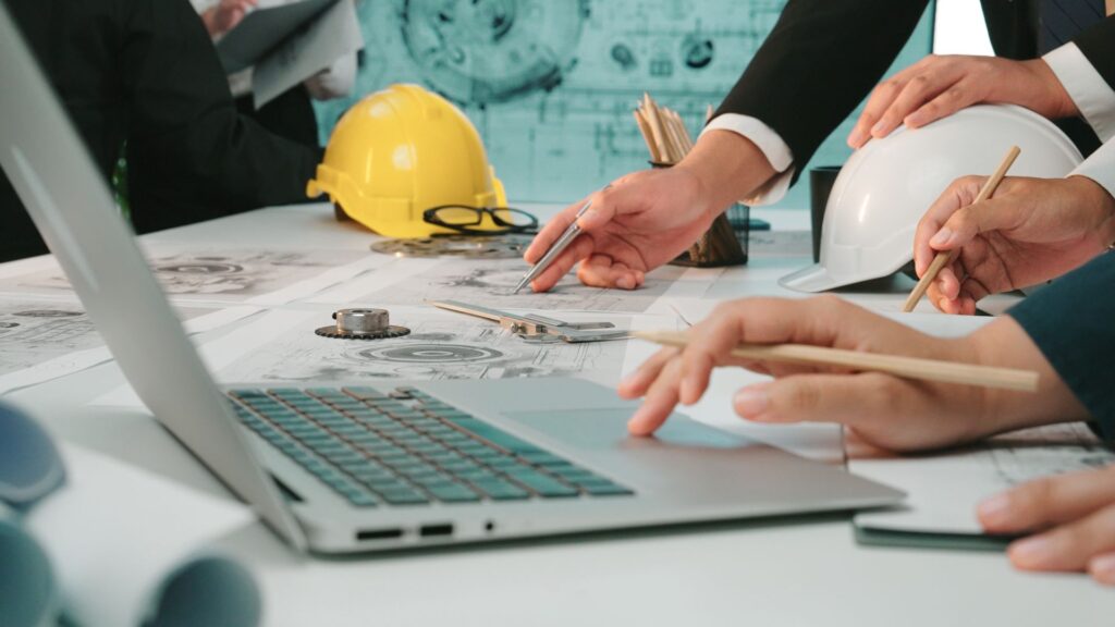 Ingenieurteam plant Montagevorrichtung am Laptop mit technischen Zeichnungen