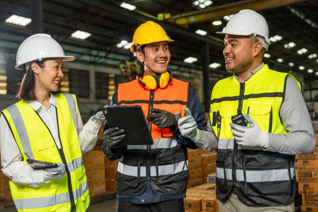Produktionsmitarbeitende mit Sicherheitsweste und Helm – Teamarbeit in moderner Fertigung